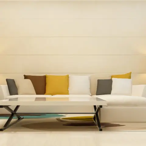 Cream sectional set symmetrically against a horizontally banded cream wall, flanked by matching glass-base lamps