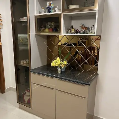 Crockery display unit with brass-trimmed glass shelves, curio figurines, a mirrored diamond-pattern backsplash