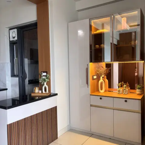 Crockery unit with bronze-tinted glass upper shutters over an LED-lit teak ledge styled with mustard bottle vases and a group of brass figurines