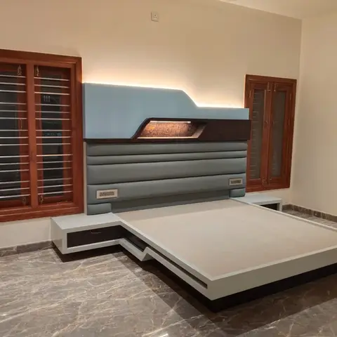 Custom platform bed with a light-blue and grey channel-upholstered headboard featuring a backlit carved wood inlay motif