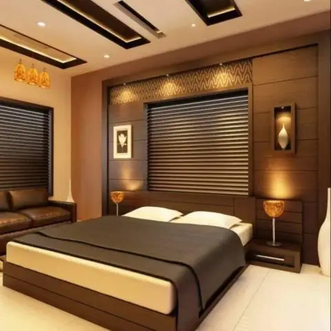 Dark walnut bedroom where a backlit wavy-textured strip runs above the headboard panelling, floating side tables carry amber globe lamps
