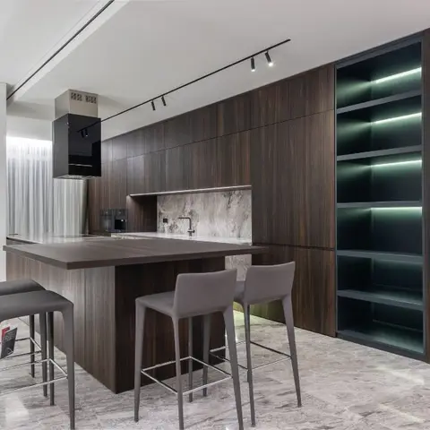 Dark wood-veneer kitchen island with a marble waterfall backsplash, grey upholstered bar stools