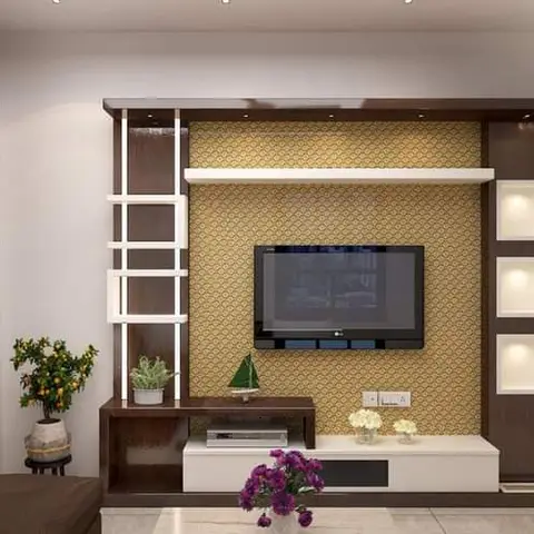 Dark wood-veneer TV unit with lit display niches and a gold patterned wallpaper backdrop, styled with potted plants on the console.