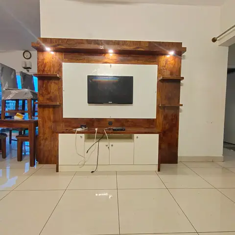 Dark wood-veneer TV unit with white lacquer base cabinets and integrated accent lighting, dining set visible behind.