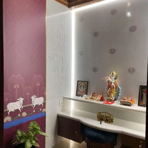 Dedicated pooja room lined in white marble etched with the Gayatri mantra and scattered lotus motifs, backlit reveals running the corner