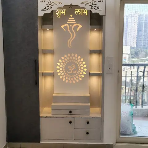 Dedicated pooja unit with a backlit white panel carrying 'Shubh Labh' script and Ganesha and Om motifs, marble-top platform with drawers below