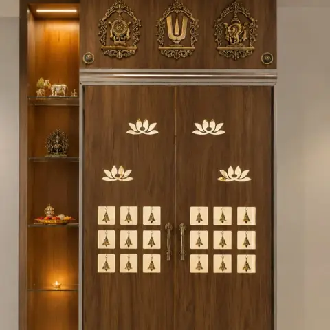 Dedicated pooja unit with dark wood double doors inlaid with brass lotus and deity motifs, ceremonial bells