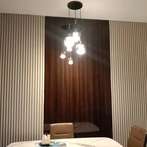 Dim dining corner where a faceted-glass cluster pendant drops over a marble-top table set against a dark walnut panel let into pale grey fluted walls.