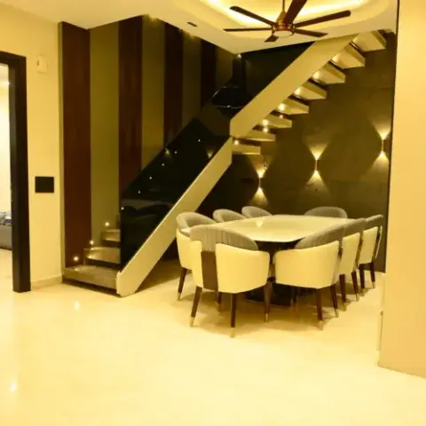 Dining area beneath a floating black-glass staircase, with a cream tufted dining chair set for eight