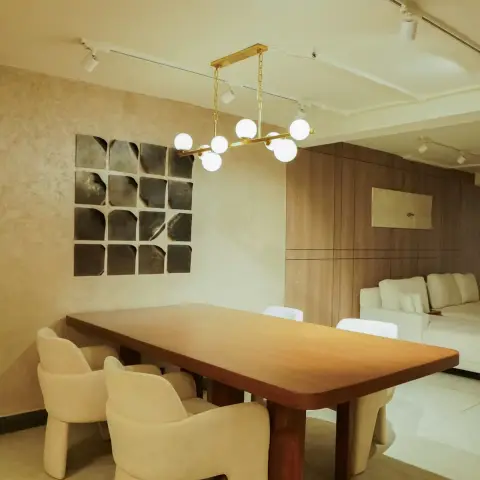 Dining area under a brass six-globe chandelier, with a solid wood table on twin slab legs