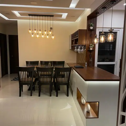 Dining area with a cluster of amber globe pendants over a dark wood dining table, and an adjoining bar counter with wine-glass racking and cage pendant lights.