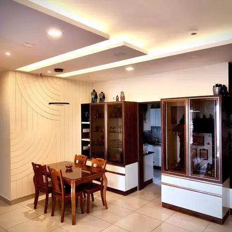 Dining area with a curved wave-groove panelled feature wall, a glass-front wood crockery unit and a glass pooja display cabinet beside the entry to the kitchen