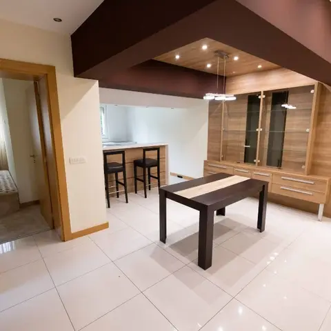 Dining area with a dark wood table, a wood-and-glass crockery display unit, and a raised cove ceiling with drop pendant lights.