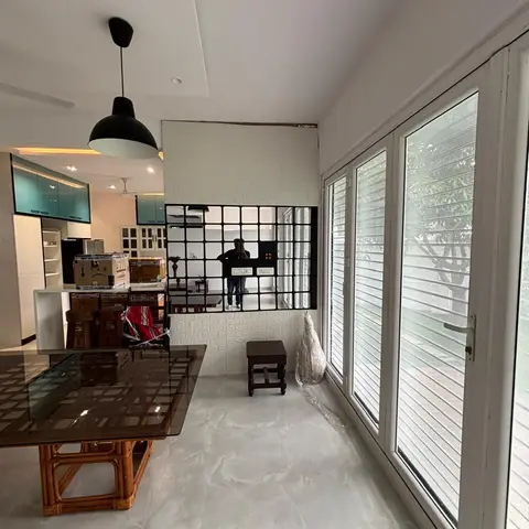 Dining area with a glass-top rattan-base dining table, a black dome pendant light and a white brick-textured accent wall opening to the kitchen.