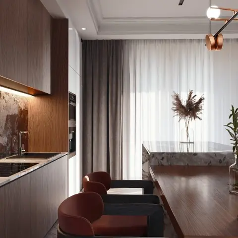 Dining area with a long wood table and rust-red upholstered chairs under a sculptural copper pendant fixture
