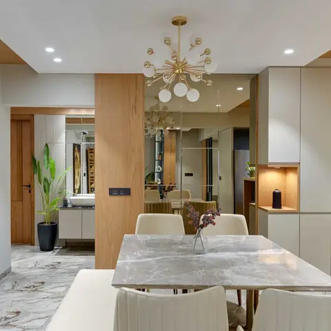 Dining area with a marble-top table, a brass sputnik chandelier and a mirrored wall reflecting the adjoining hallway.