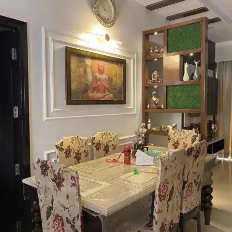 Dining area with a marble-top table under floral slipcover chairs, a framed Buddha painting on a moulded wall panel