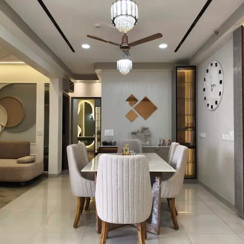 Dining area with a marble-top table, channel-tufted beige chairs, twin crystal pendant lights and a diamond-mirror accent wall beside a fluted gold-trim
