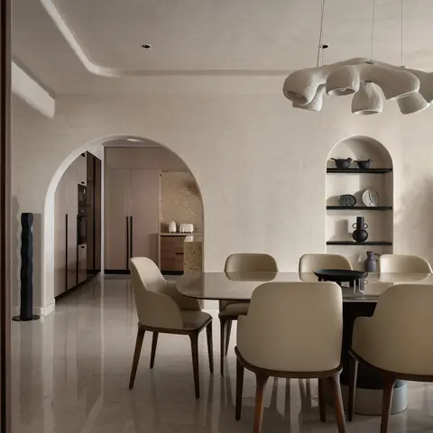 Dining area with a sculptural cream ceramic pendant light over an oval marble-top table with cream leather chairs