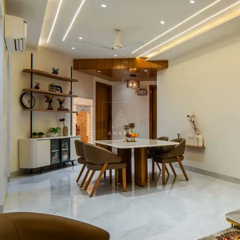 Dining area with a square marble-top table on a fluted wood pedestal and four tan leather tub chairs