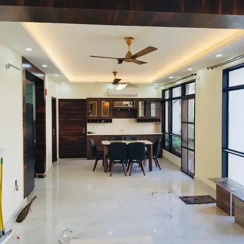 Dining area with a wood dining table and black chairs, a mirrored crockery unit against the back wall, two ceiling fans under a cove-lit ceiling