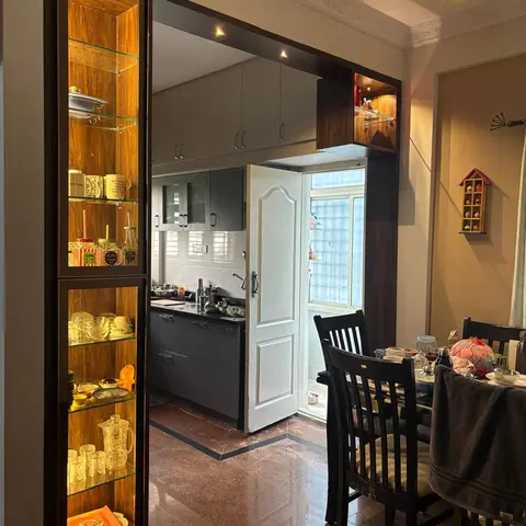 Dining area with a wood-framed backlit glass display cabinet, a dark wood dining table and chairs, decorative ceiling cornice moulding