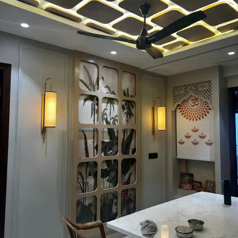 Dining corner lit by a dropped ceiling grid of backlit rounded squares with a black fan hung through it