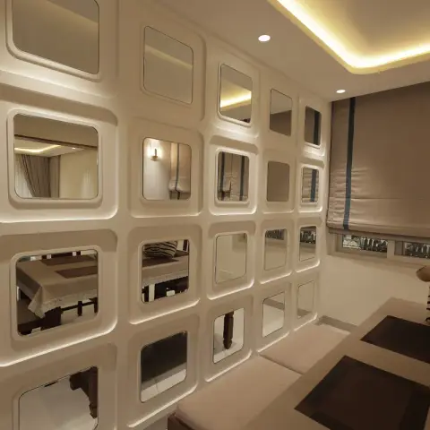Dining nook divided by a striking grid-patterned mirror partition wall under a cove-lit ceiling