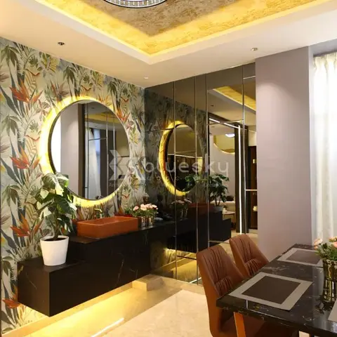 Dining nook with a black-and-gold marble table and rust leather chairs beside a floral tropical-wallpaper wall with a round backlit mirror over a floating