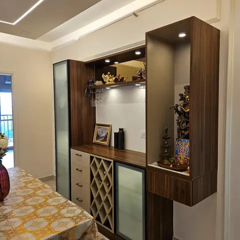 Dining nook with a combined walnut-finish bar and pooja display unit — a wine-glass rack and frosted-glass bar cabinet on the left