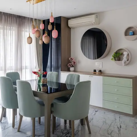 Dining nook with a dark wood table, sage-green velvet chairs, a cluster of blush-pink glass pendant lights