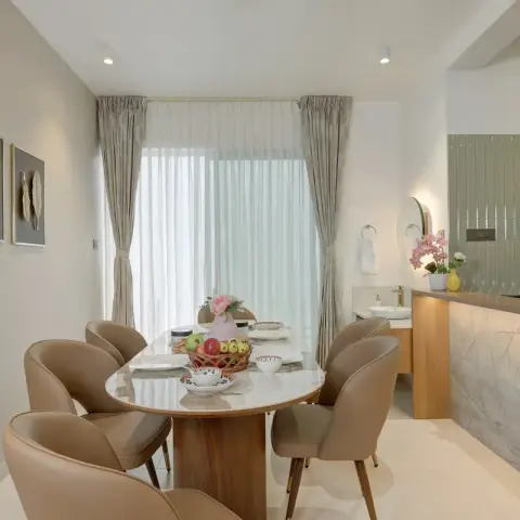Dining nook with a marble-top oval table and six tan leather chairs in front of sheer curtained windows