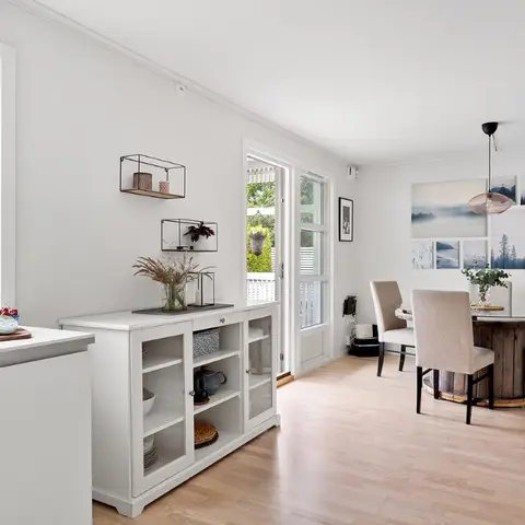 Dining nook with a round reclaimed-wood-base table and beige upholstered chairs, a woven pendant light overhead