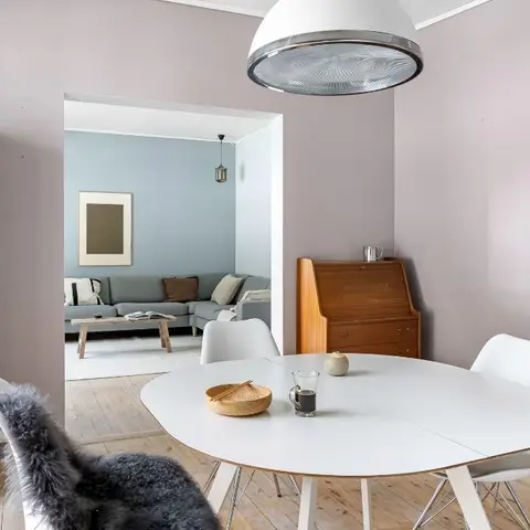 Dining nook with a round white table and Eames-style chairs under a large dome pendant light, a vintage wood bureau in the corner