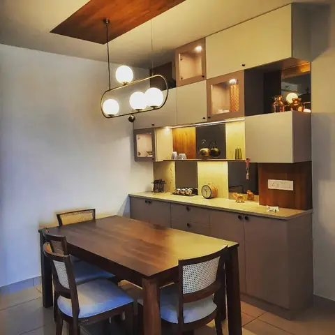 Dining nook with a wood table and cane-back chairs beneath a multi-globe brass pendant light