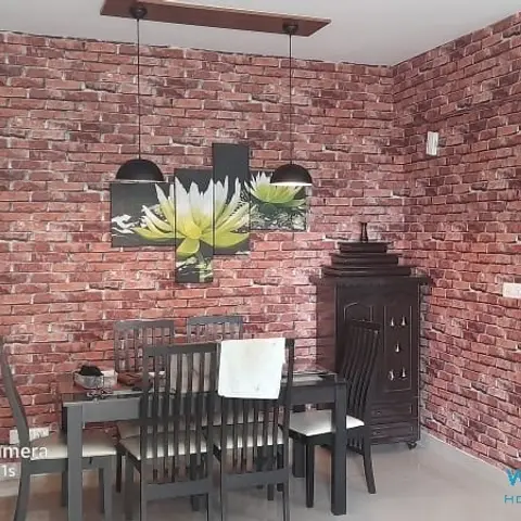 Dining nook with brick-effect wallpaper, twin black pendant lights over the table, and a dark wood crockery cabinet in the corner.
