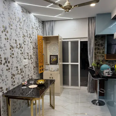 Dining nook with floral gold-and-grey wallpaper, a black-and-gold marble-top table, and an open built-in pooja unit with jaali door beside the balcony entrance.