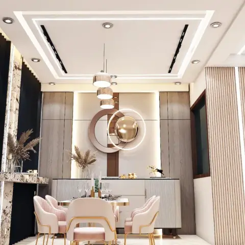 Dining nook with pink velvet chairs, a brass ring-sculpture mirror, and fluted wood panelling under a cove-lit ceiling.