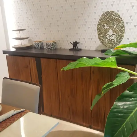 Dining room console styled with ceramic jars, a cake stand and metal sculptures against triangle-patterned wallpaper