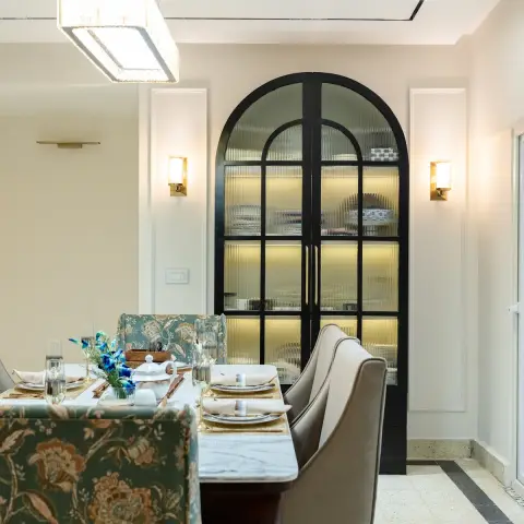 Dining room set for six around a marble-top table, mixing two green floral-chintz wing chairs with taupe leatherette ones
