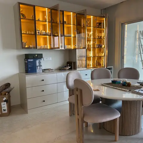 Dining room with a backlit glass-front crockery cabinet over a glossy white sideboard