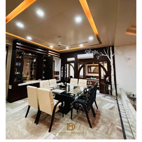 Dining room with a black glass-top table seating eight in cream and patterned upholstered chairs, a dark wood mirrored display cabinet
