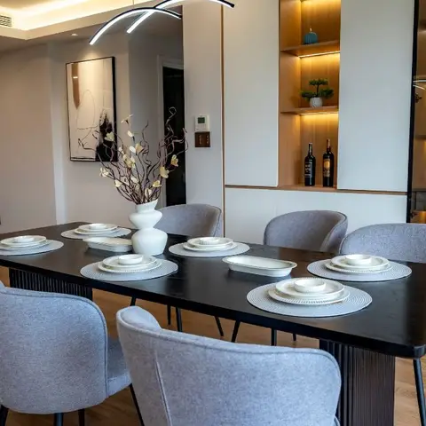 Dining room with a black wood table set for six on textured placemats, grey upholstered chairs