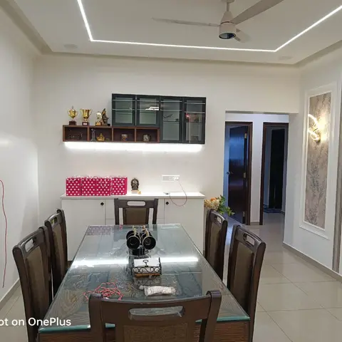 Dining room with a glass-top wood table for six, a cove-lit ceiling, and a glass-front display cabinet over a white sideboard.