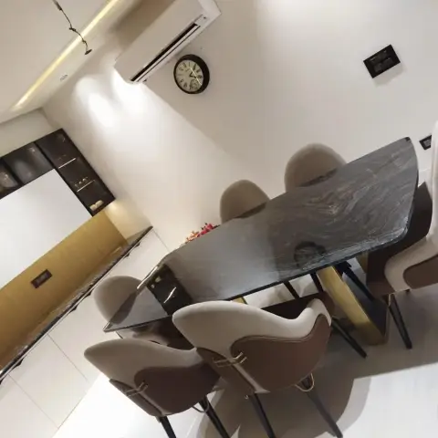 Dining room with a live-edge black stone slab table on a gold pedestal base, two-tone tan-and-brown upholstered chairs