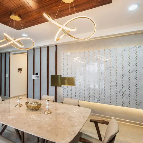 Dining room with a marble feature wall inlaid with gold chevron strips, sculptural infinity-loop gold pendant lights