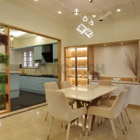 Dining room with a marble-top table for six beneath a geometric pendant chandelier, wood-framed display shelving with a lit pooja niche