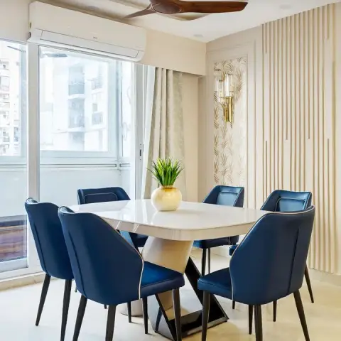 Dining room with a marble-top table, six navy-blue upholstered chairs, fluted wood wall panelling
