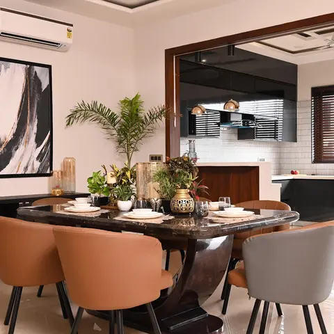 Dining room with a marble-top table on a sculptural wood pedestal and tan/grey leather chairs, an abstract black-and-gold canvas on the wall