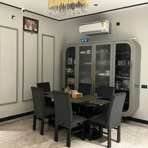 Dining room with a rounded grey crockery unit featuring fluted glass doors and brass trim, a six-seater dark dining table with grey upholstered chairs